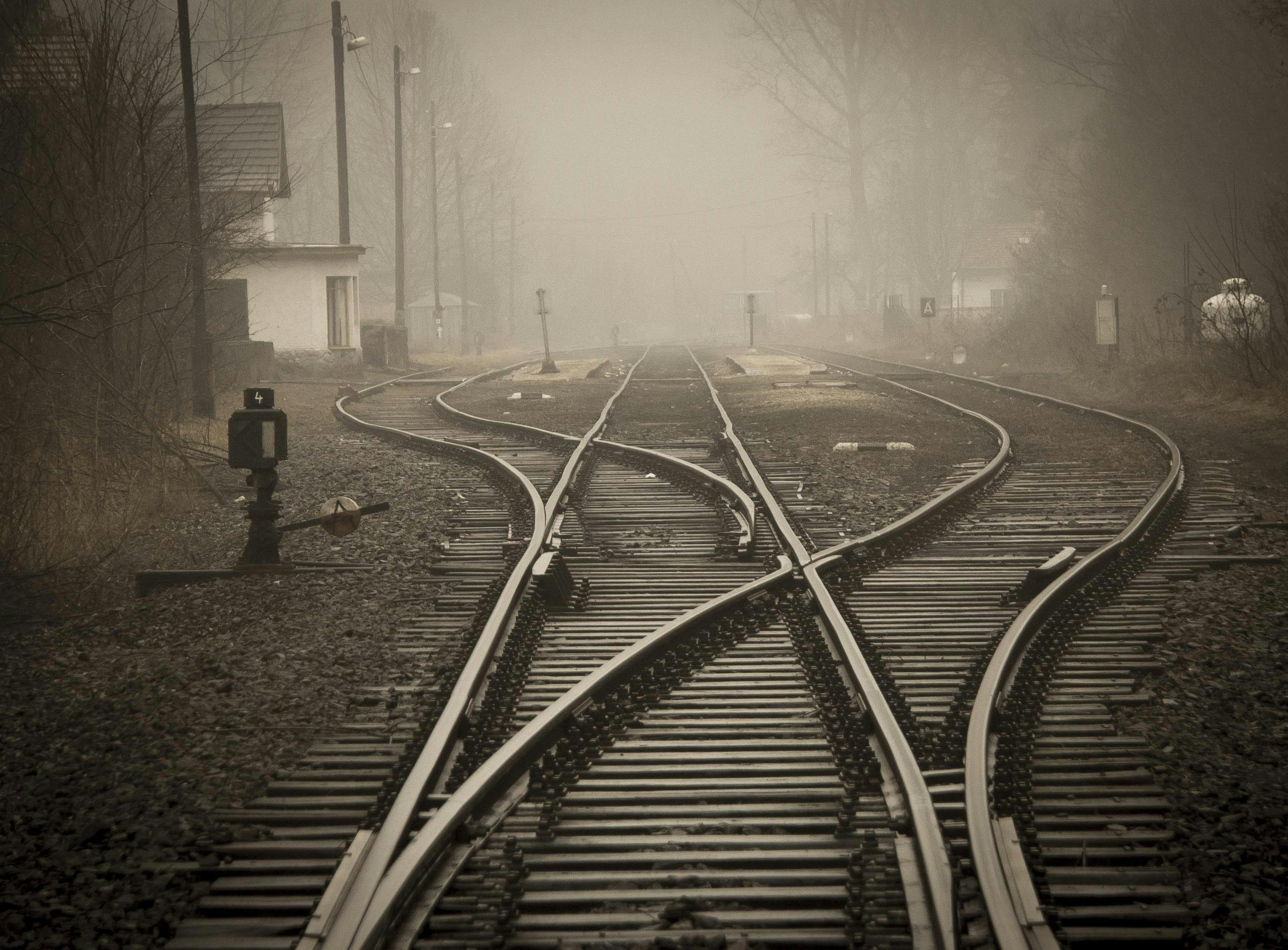 Des voies ferrées divergentes dans une brume épaisse, symbolisant les choix et les chemins multiples de la vie.